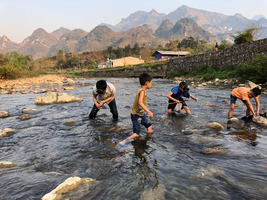 The kids are catching fish in the stream in Du Gia - 1 of top 4 unspoiled ancient villages in Ha Giang